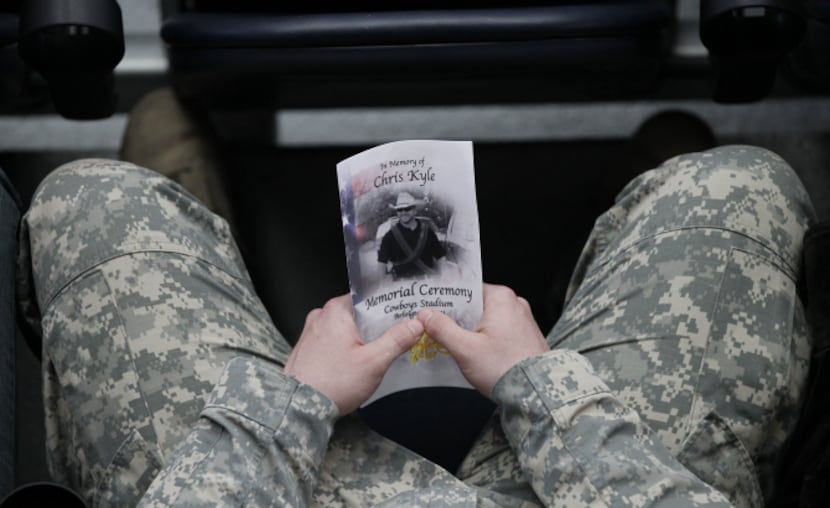 A person holds a program during a memorial service for Chris Kyle at Cowboys Stadium in...