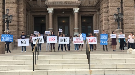 Protesters with the Texas Freedom Network hold signs outside the Texas Capitol on Thursday...