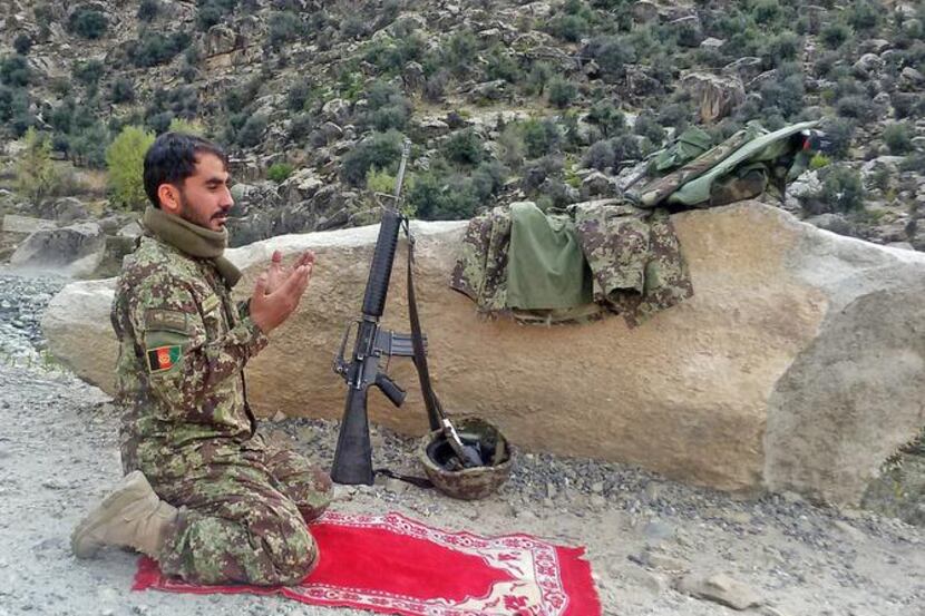 
An Afghan army soldier prayed while fighting Taliban insurgents last week in the rugged...