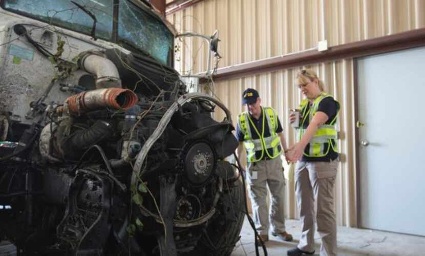 
In this photo provided by The National Transportation Safety Board, officials examine part...