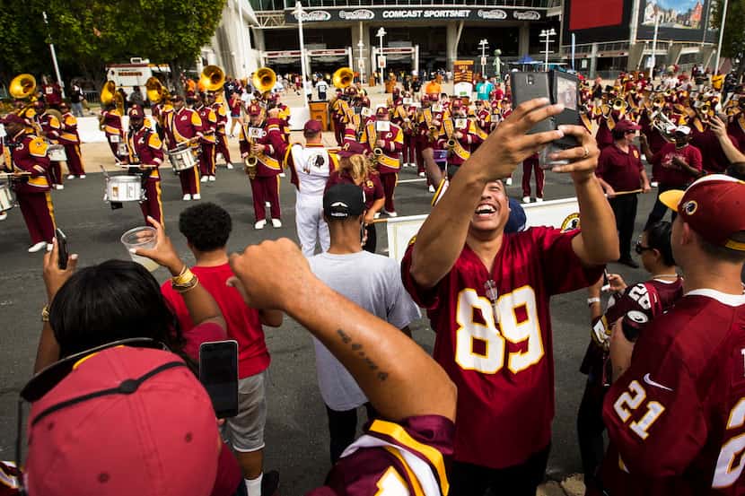 The Washington Redskins Marching Band preforms outside the stadium as fans tailgate before...