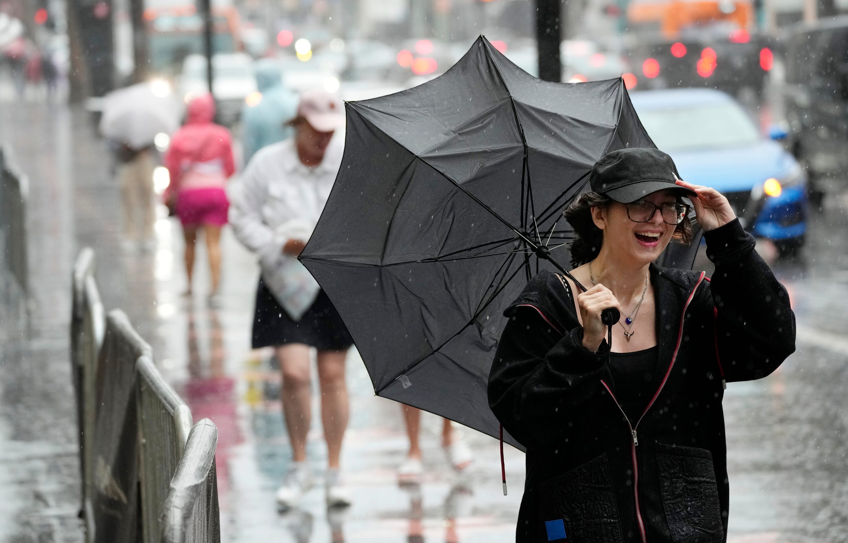 A pedestrian walks through strong winds and rain from Tropical Storm Hilary on Hollywood...