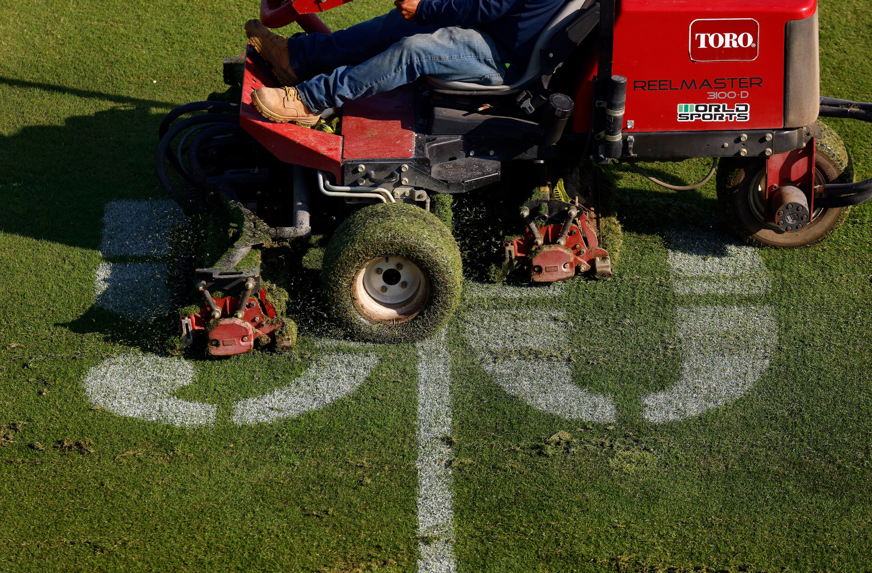 Grounds crewman Alberto Ortega cuts the grass fields in preparation for the Dallas Cowboys...