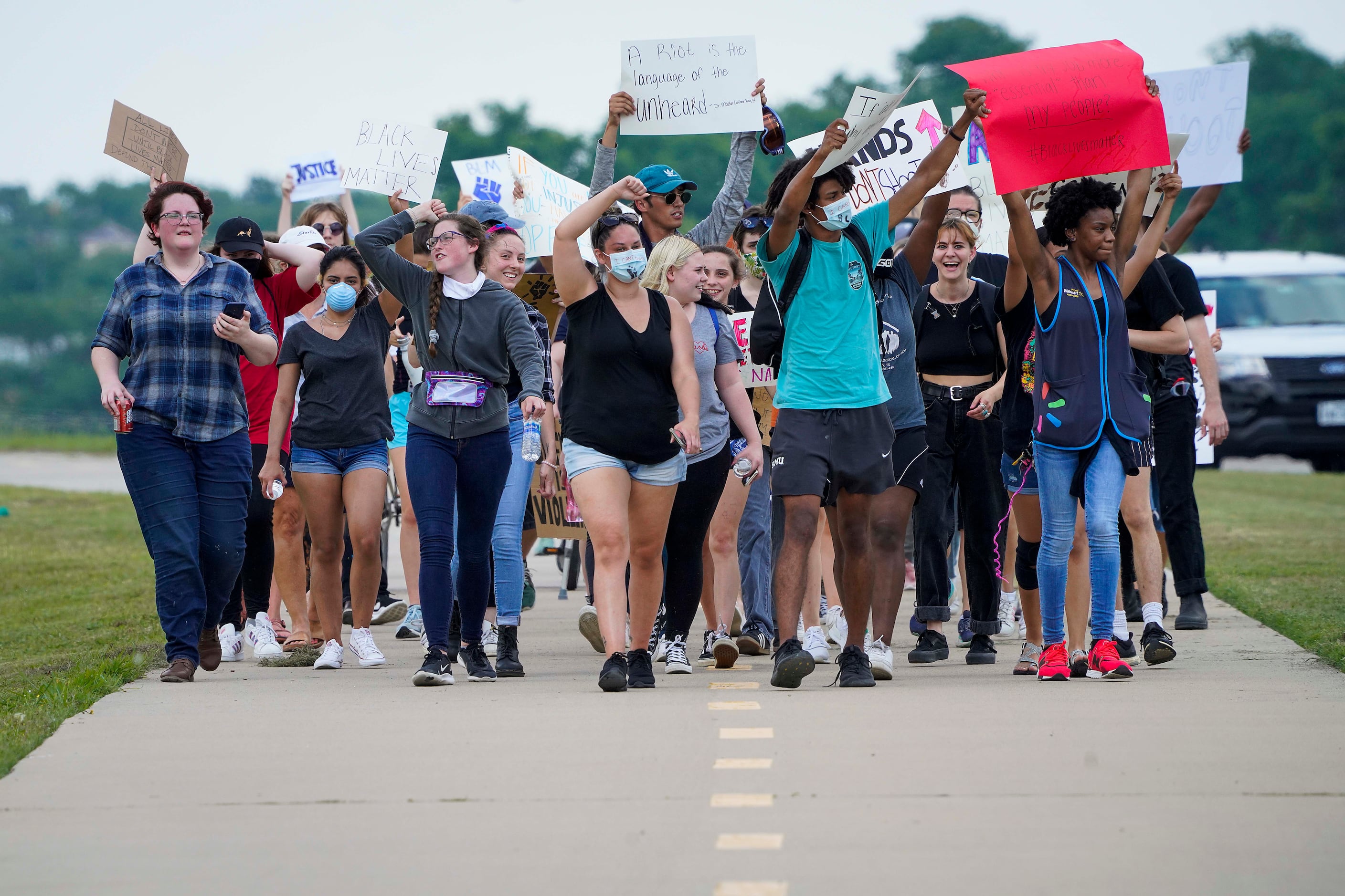 A group of demonstrators marches on a bike path along Northwest Highway near Flagpole Hill...