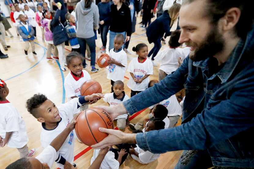 Tyler Shafer with Looney and Associates ( right, hands out a basketball to excited students...