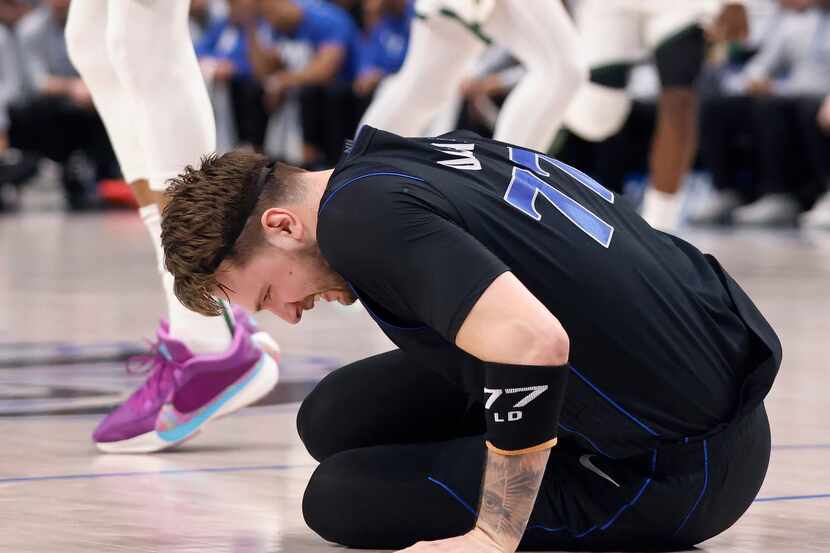 Dallas Mavericks guard Luka Doncic (77) winces in pain after sustaining a first quarter...