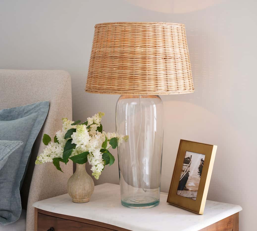 Table lamp with clear glass cylindrical base and natural woven lampshade