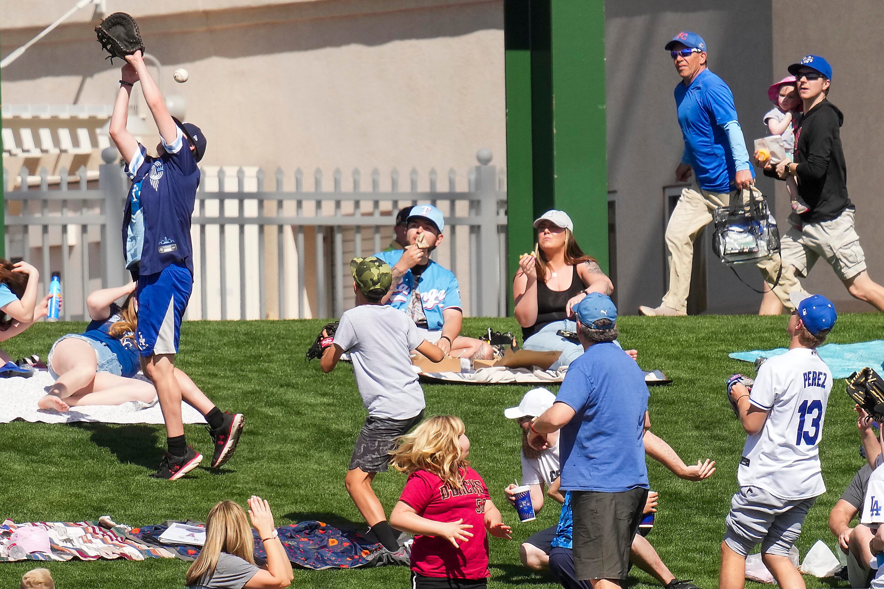 A fan on the outfield berm tries to make a play on a home run off the bat of Kansas City...