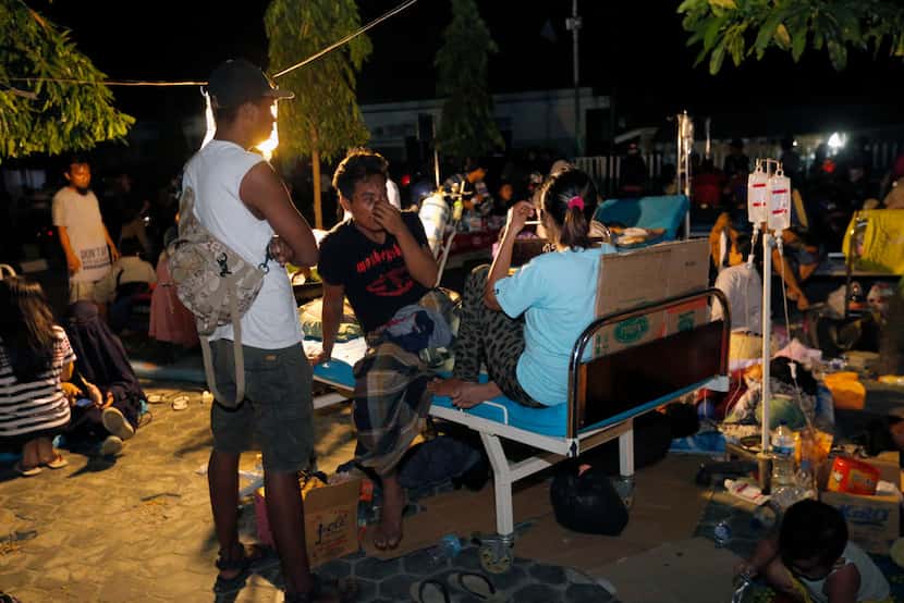Injured people are treated outside at Army hospital following earthquakes and a tsunami in...
