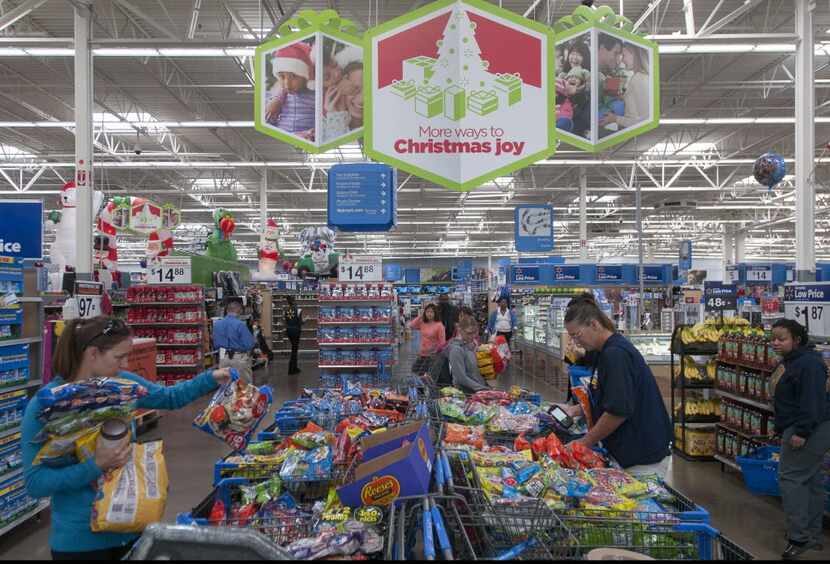 Walmart customers pick out marked down Halloween candy as employees sort and price it at the...