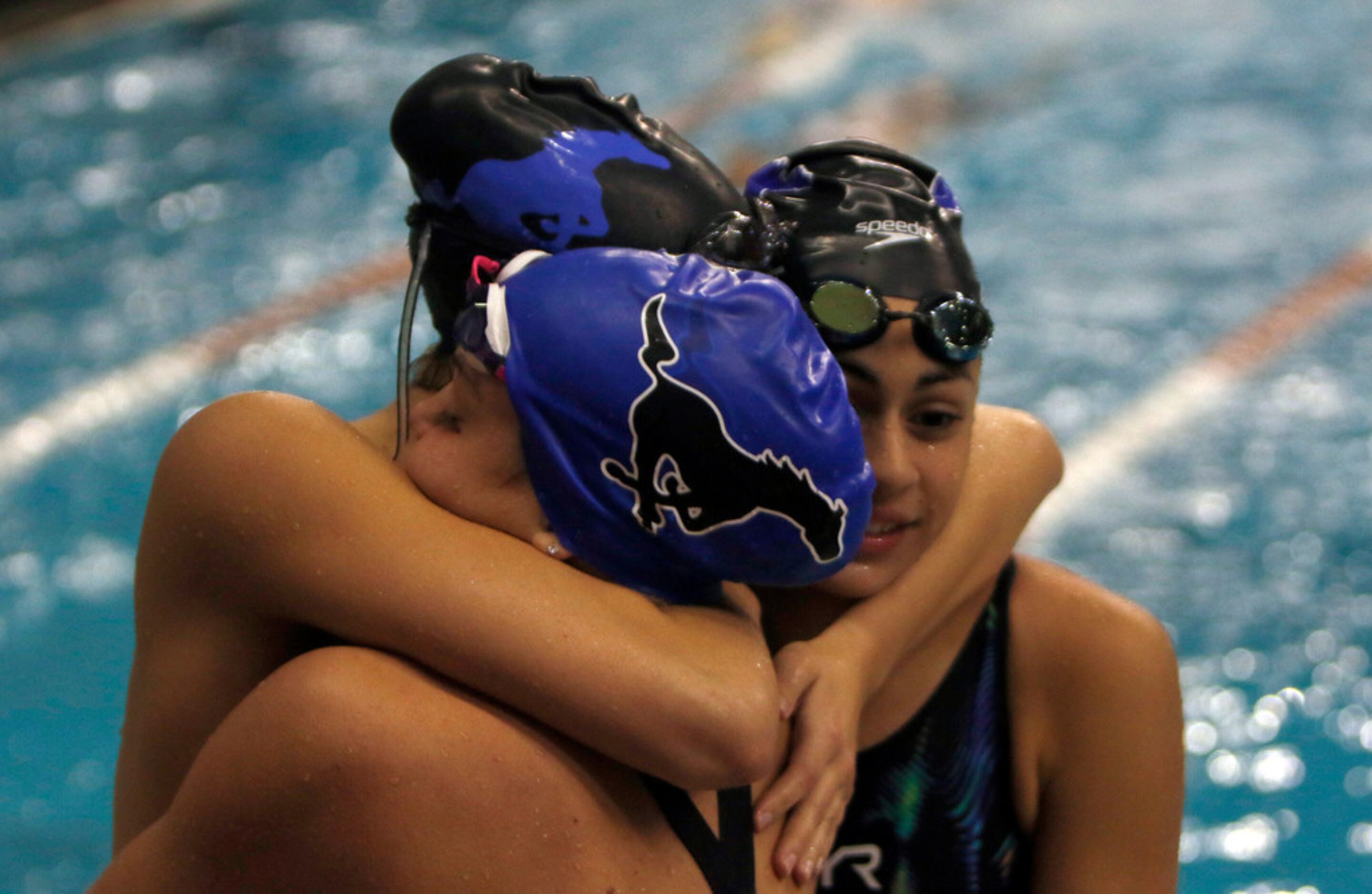 A trio of athletes hug following their swimming event. The UIL Class 6A state swimming and...