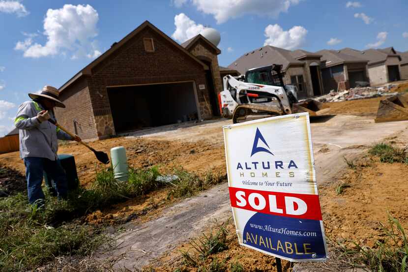Construction workers build Altura single-family homes in the River Ridge community in...