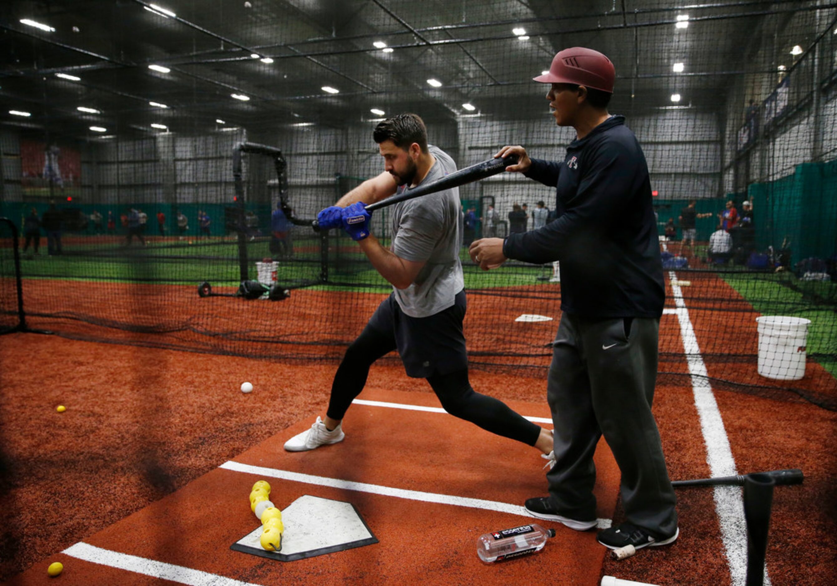 Texas Rangers Joey Gallo (13) works with Texas Rangers hitting coach Luis Ortiz (18) in the...