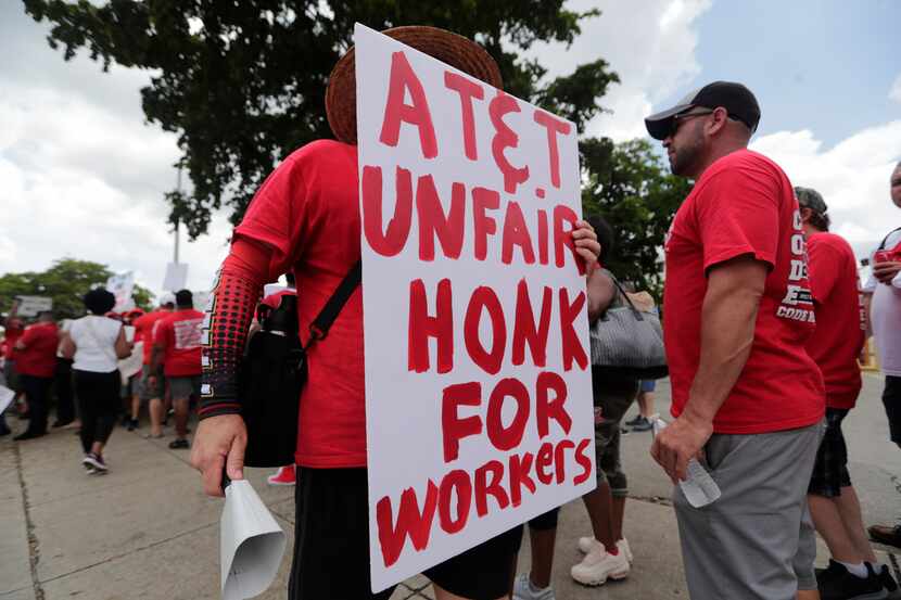 Members of the Communications Workers of America walk a picket line outside of an AT&T...