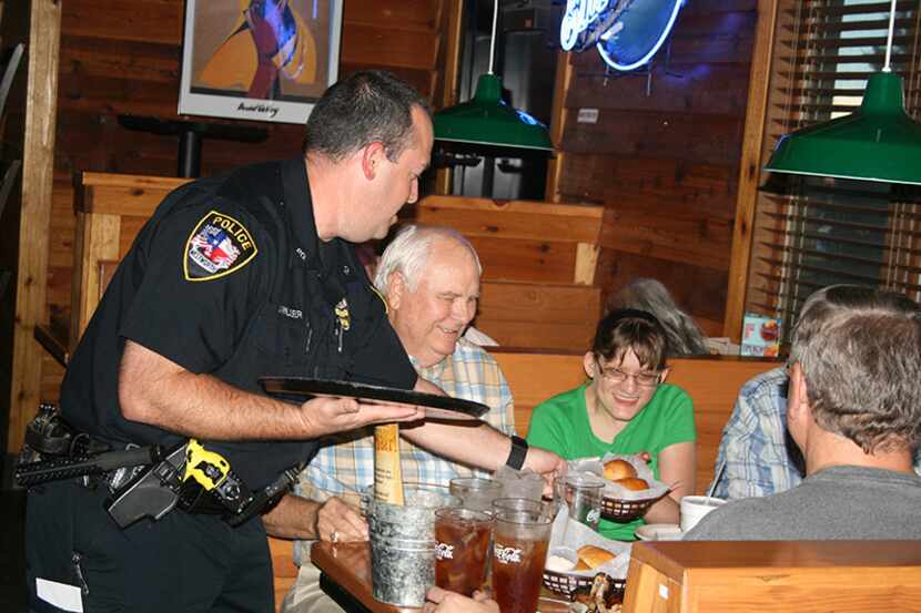  Westworth Village Police Officer Jeramy Miller serves hot rolls to the Crump family of Fort...