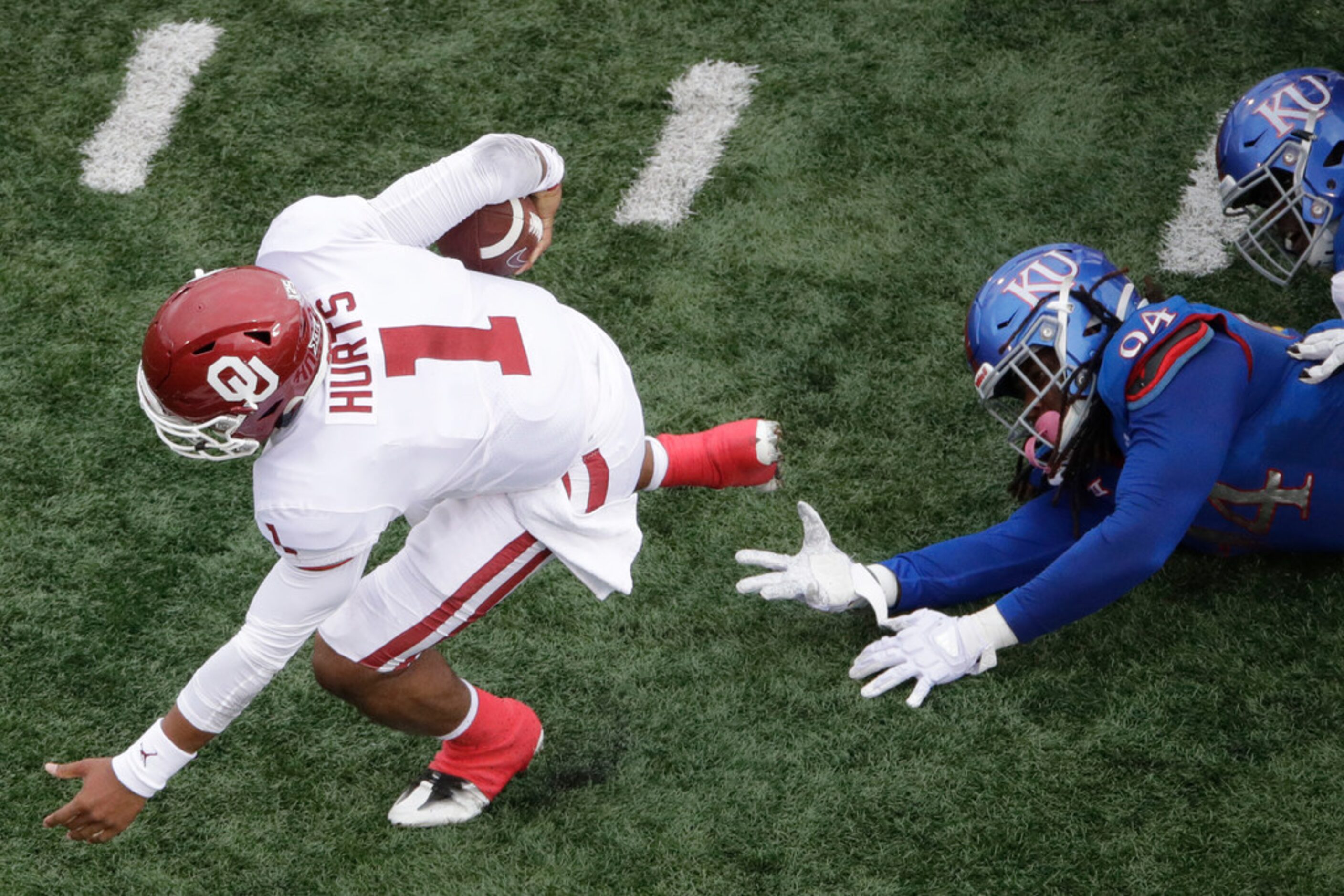 Oklahoma quarterback Jalen Hurts (1) gets past Kansas defensive end Codey Cole III (94) as...