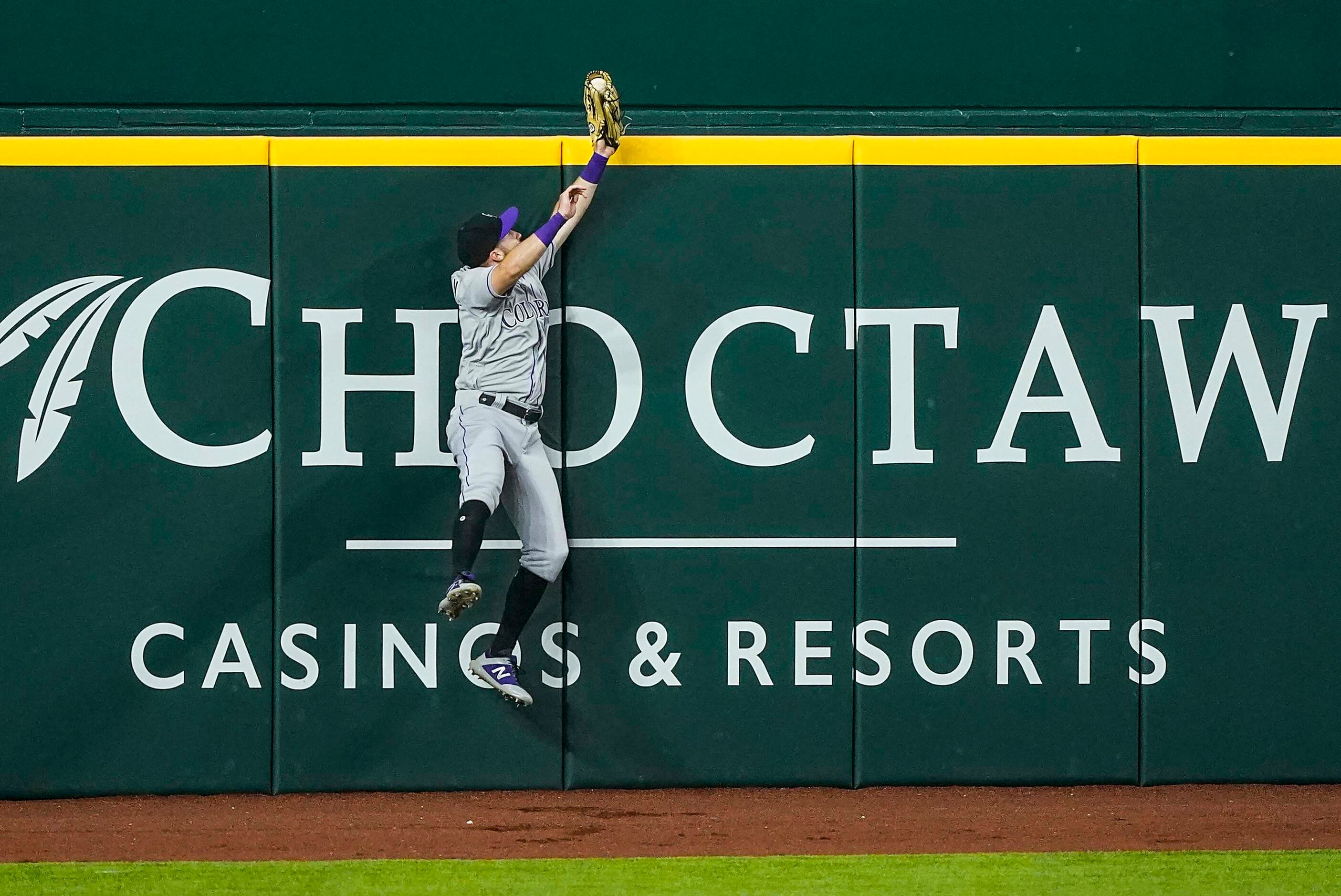 Colorado Rockies left fielder Garrett Hampson makes a leaping play at the wall to rob Texas...