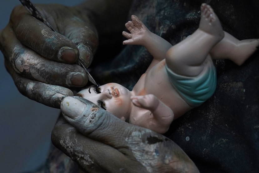 Un hombre repara una estatua del niño Dios en preparación para la fiesta del "Día de la...