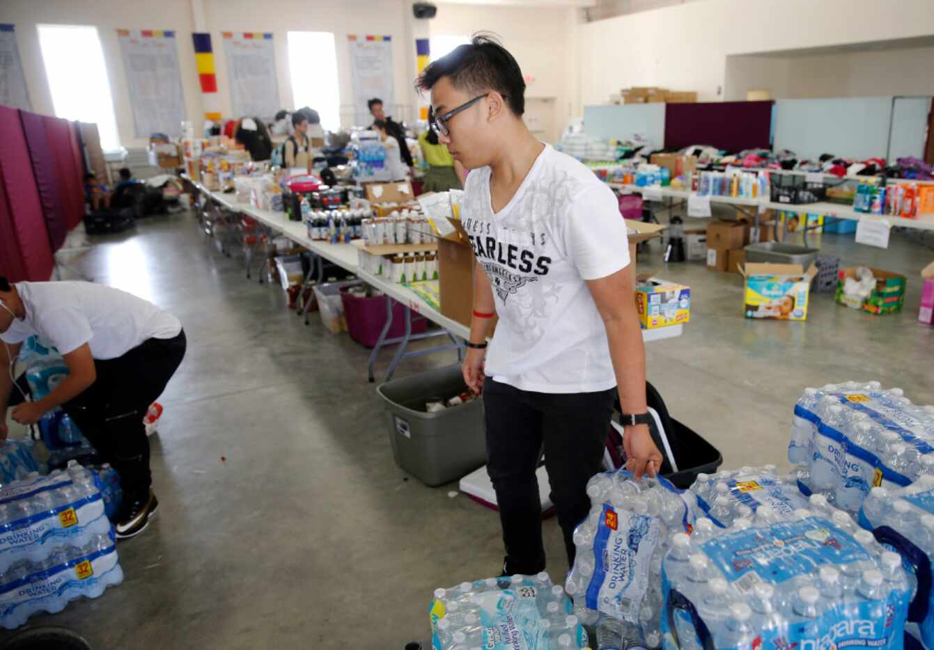 Huy Huynh works on stocking cases of water in a donation area for hurricane Harvey victims...