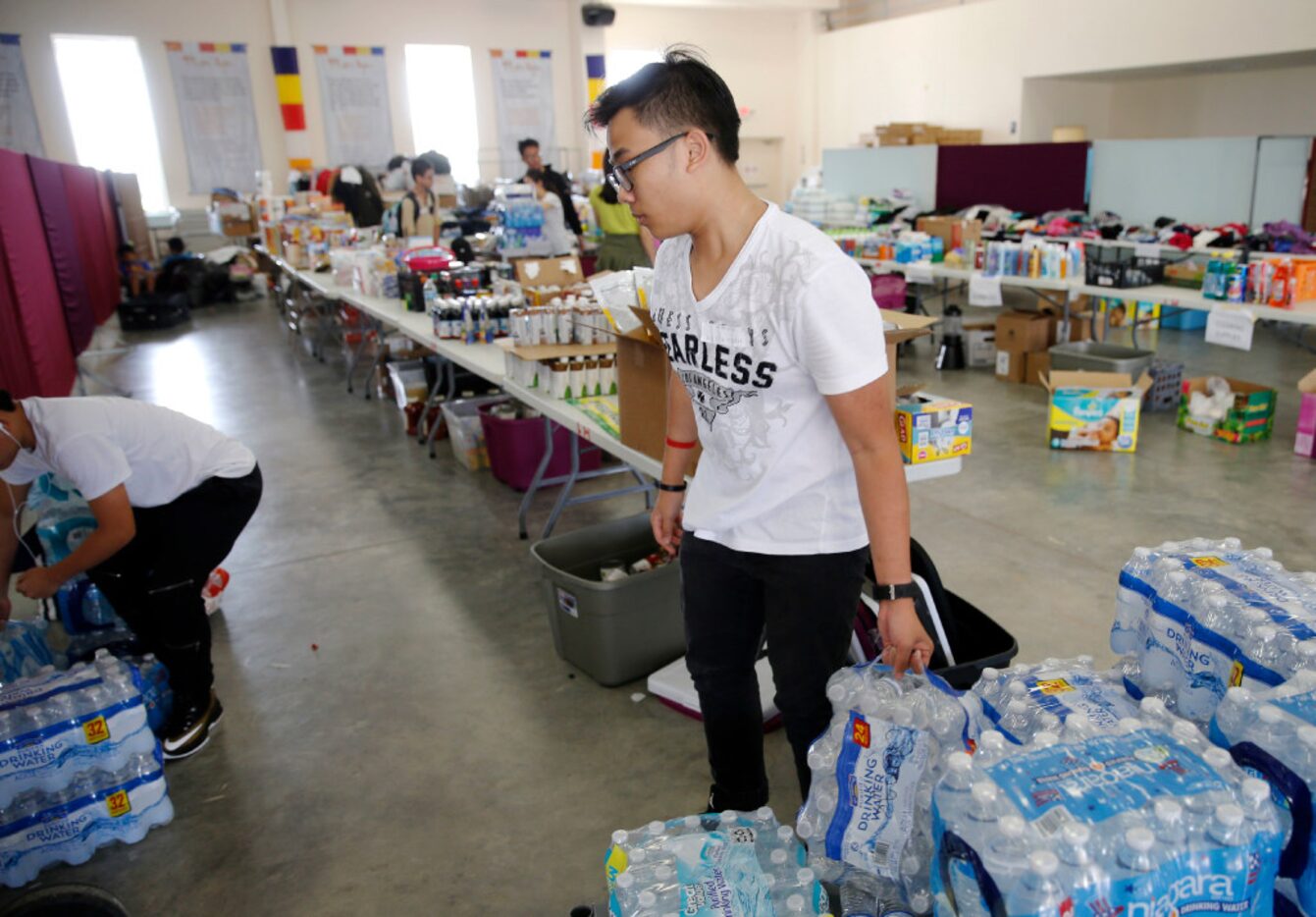 Huy Huynh works on stocking cases of water in a donation area for hurricane Harvey victims...