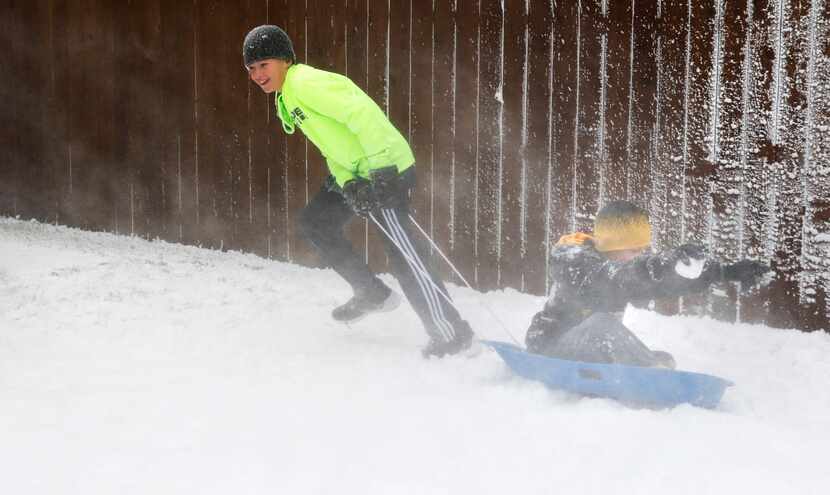 Jude Melchiorre, 12, left, pulls his brother, Christian, 9, in the "snow."