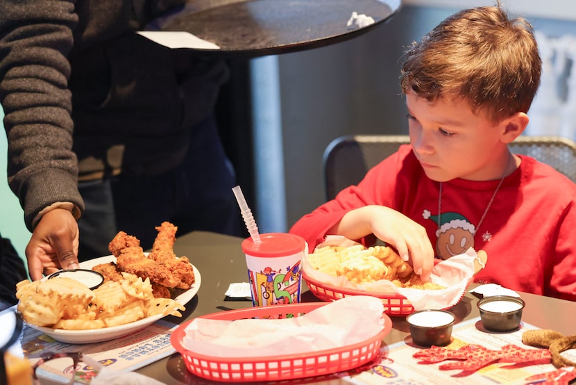 James Cottrell, 7, eats his meal during Pluckers' annual charity event on Tuesday, Dec. 24,...