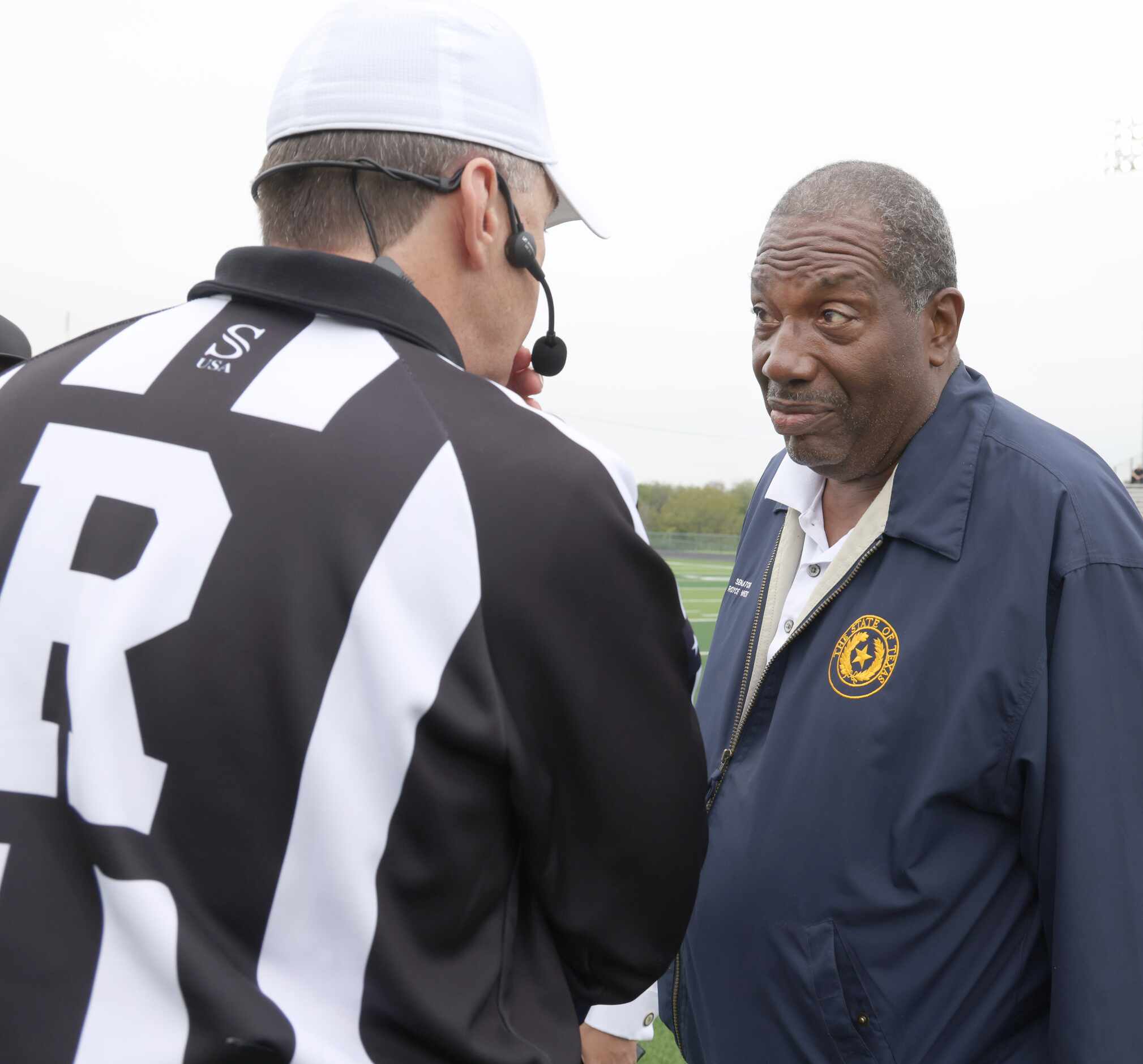 Texas State Senator Royce West, right, speaks with a game official before flipping the coin...