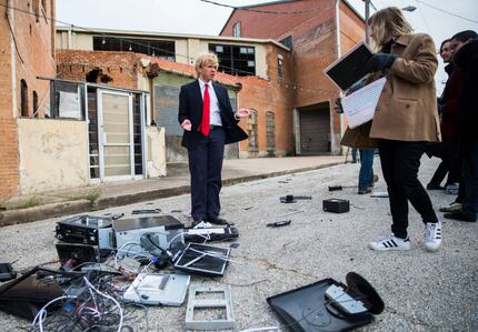 Dalton Fowler, who impersonates Donald Trump, stands over a pile of destroyed electronics...