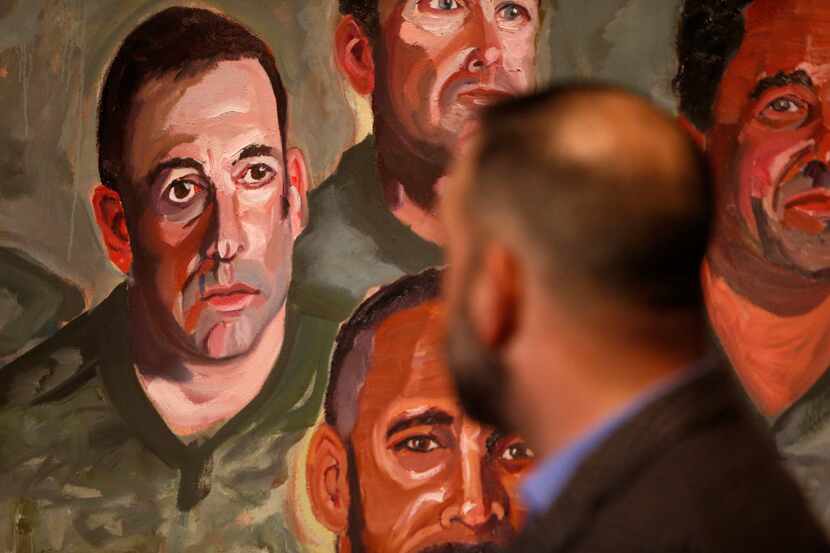 First Sgt. Robert Ferrara looks over at his portrait during a media preview of the Portraits...