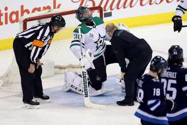 Stars goaltender Ben Bishop (30) is attended to by team staff for an apparent injury after...