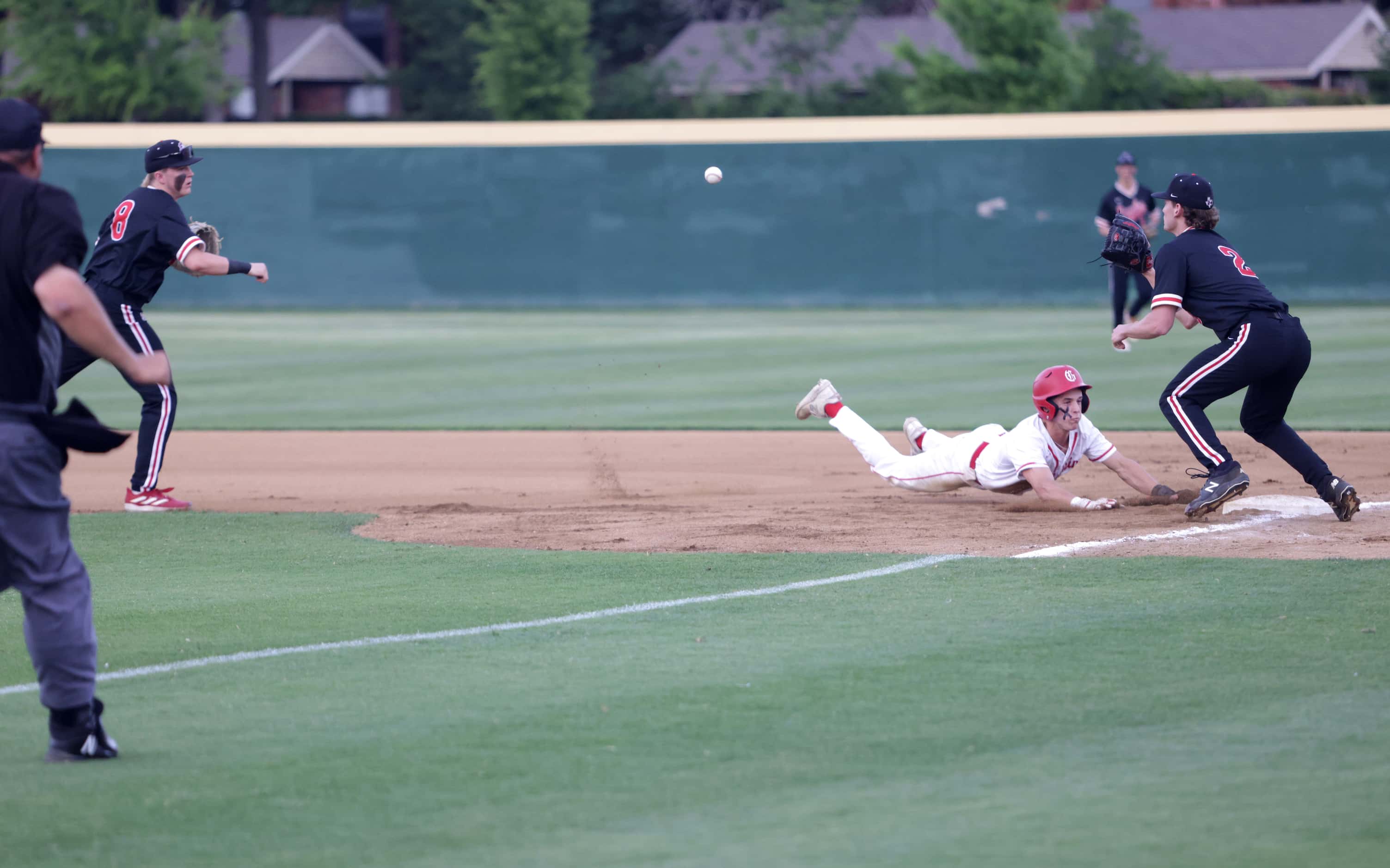Grapevine High School player Sammy Kelley slides to beat the ball during a baseball game...