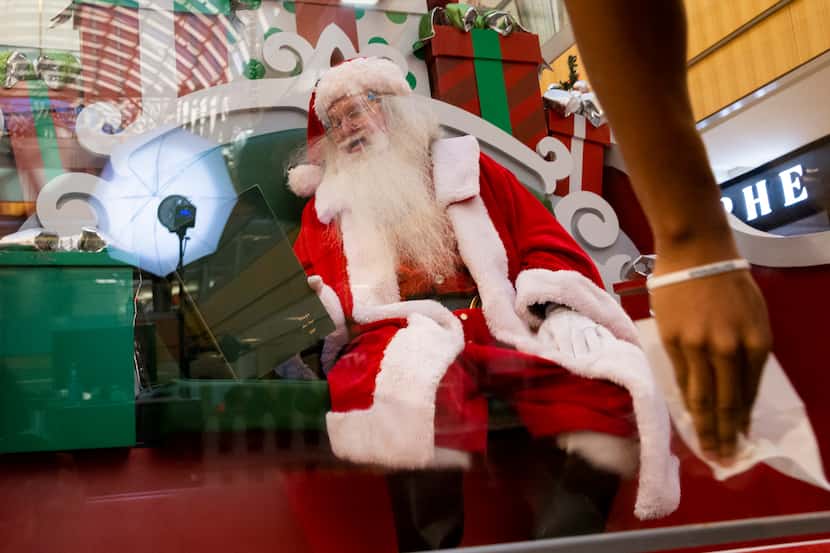Santa Claus sits behind a screen as it gets desensitized at the Galleria in Dallas on...