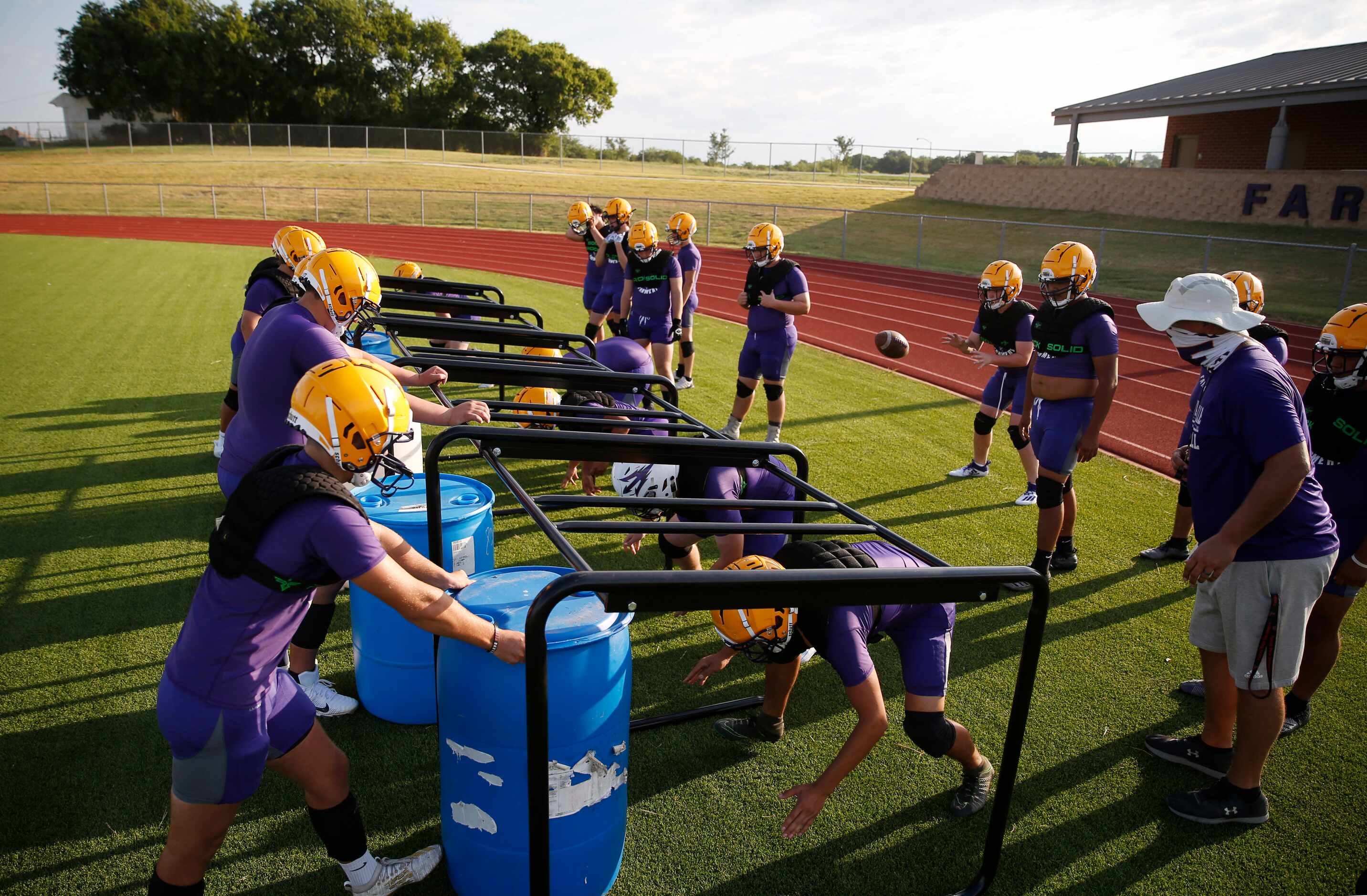 Farmersville's linemen run through a drill during the first day of high school football...