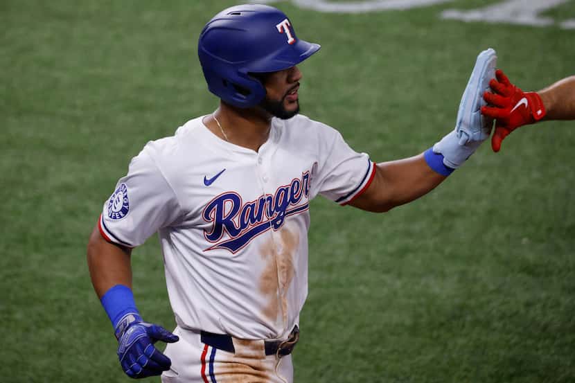 Texas Rangers outfielder Leody Taveras (3) gets a high-five after scoring on a single by...