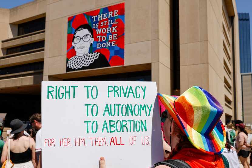 An abortion rights supporter raises a sign in front of a mural of Ruth Bader Ginsburg,...