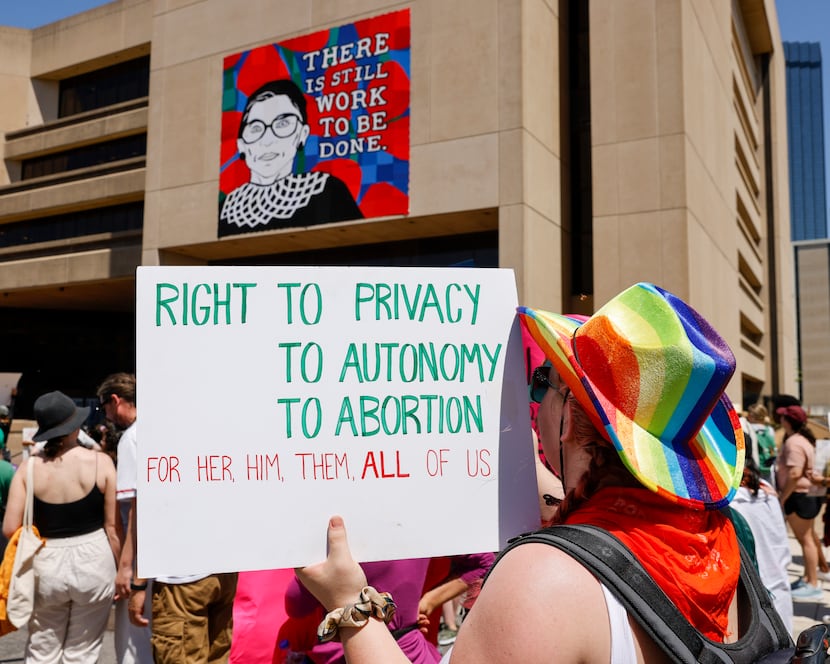 An abortion-rights supporter raises a sign in front of a mural of Ruth Bader Ginsburg,...