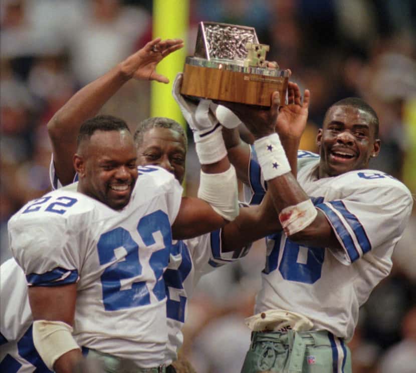 Dallas Cowboys' Emmitt Smith (22) and Michael Irvin hold up the NFC Championship trophy...