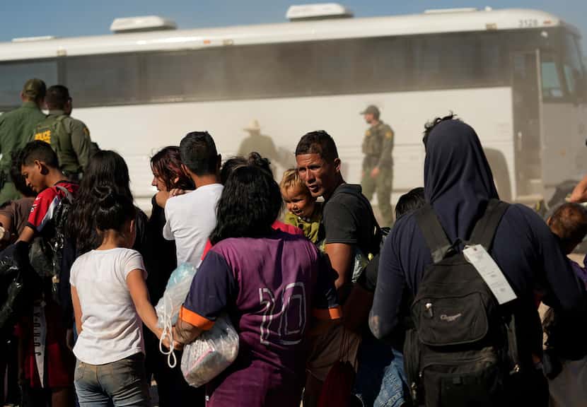 Migrants wait to board busses as they are processed by the U.S. Customs and Border Patrol...