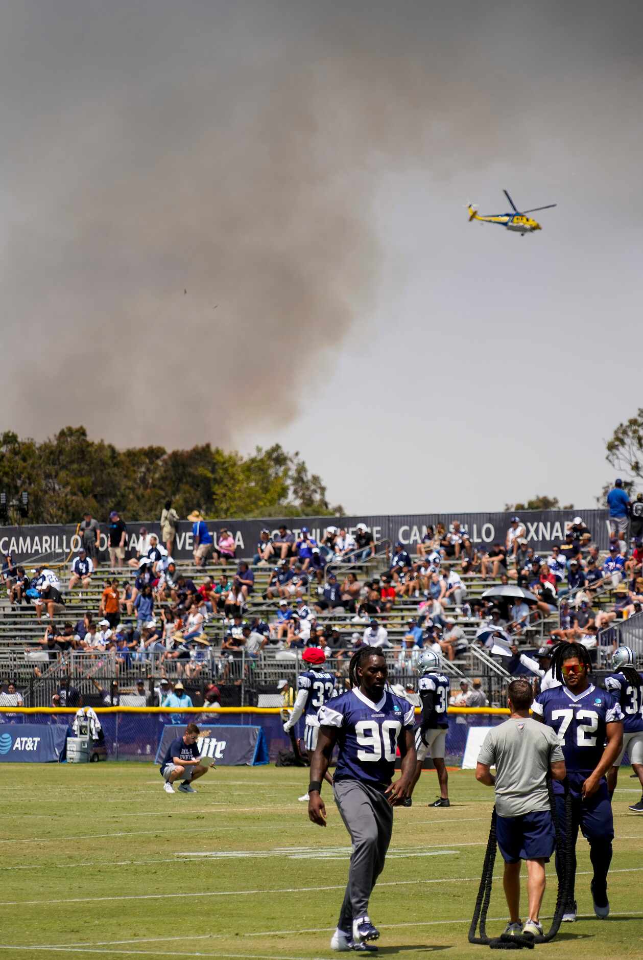 A firefighting helicopter works to control a fire near the facility as the Dallas Cowboys...