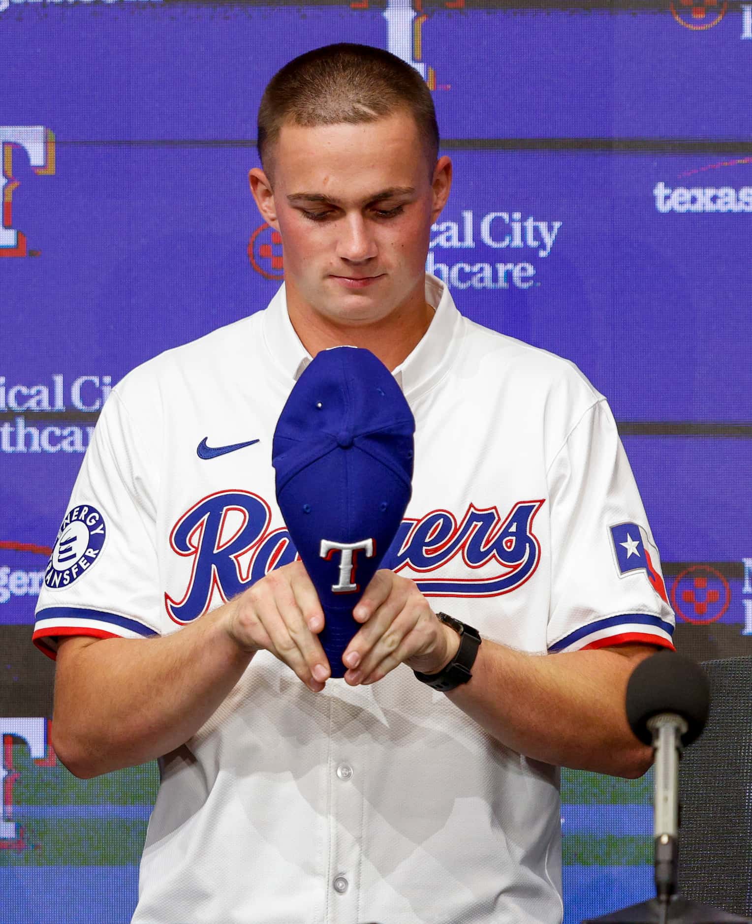 Texas Rangers first-round pick Malcolm Moore bends his Rangers hat before putting it on...