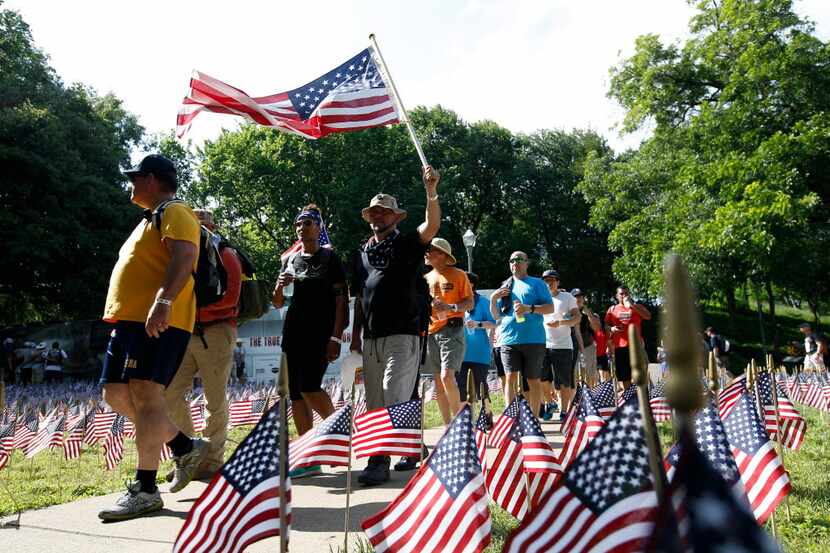 Army veteran Hugo Lopez(center) of Arlington carries a US Flag with wife Veronica, also an...