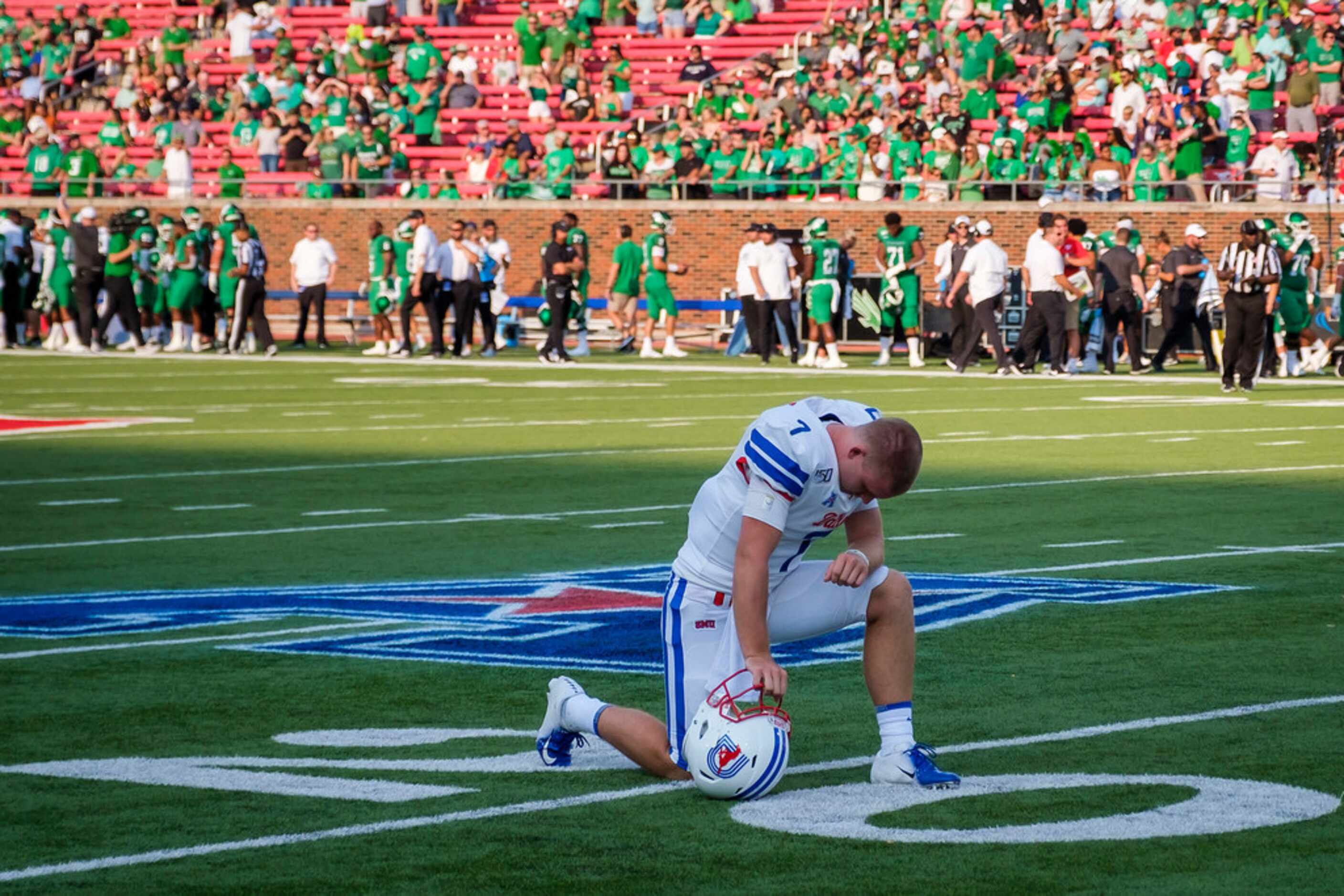 SMU quarterback Shane Buechele kneels in prayer at the 20-yard line before an NCAA football...