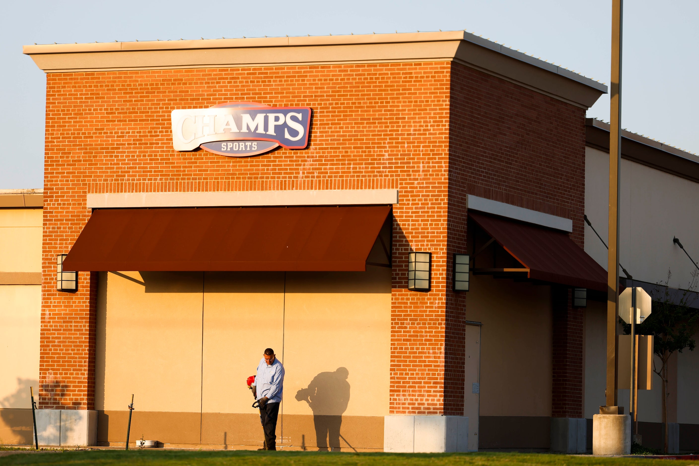 A landscape worker works outside of the north entrance of Allen Premium Outlets mall on the...