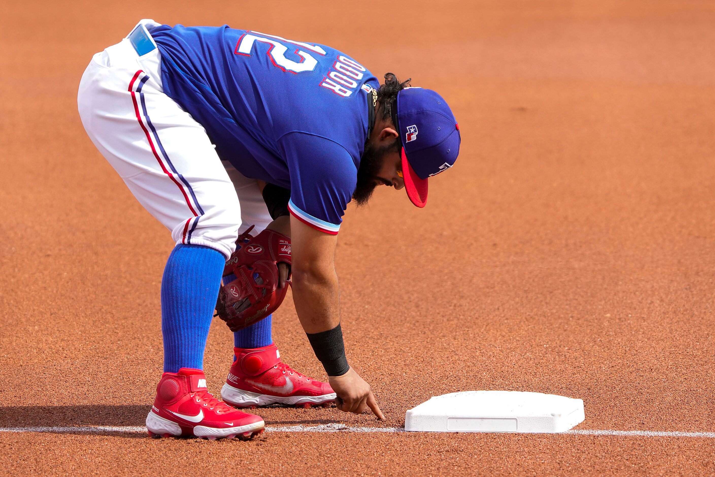 Texas Rangers third baseman Rougned Odor writes in the dirt behind the third base bag before...