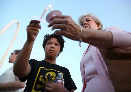 Linda Roden (right) lights Mary Ann Munoz's candle during a vigil honoring Antoinette Brown...