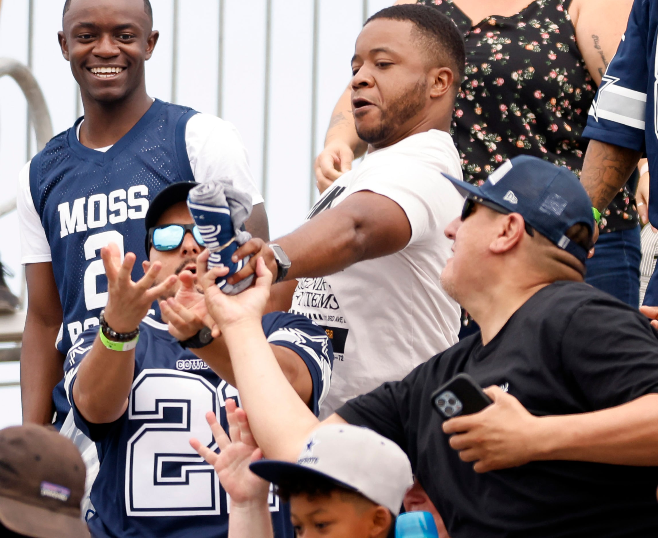 The Dallas Cowboys fans in the stands reach for a thrown t-shirt thrown their way during the...