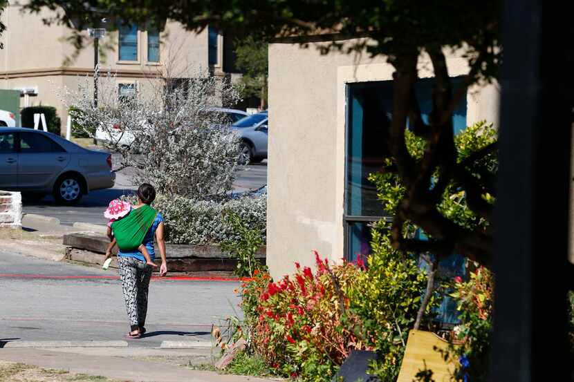 A woman walks with her baby in The Ivy Apartments in the Vickery Meadow neighborhood in...