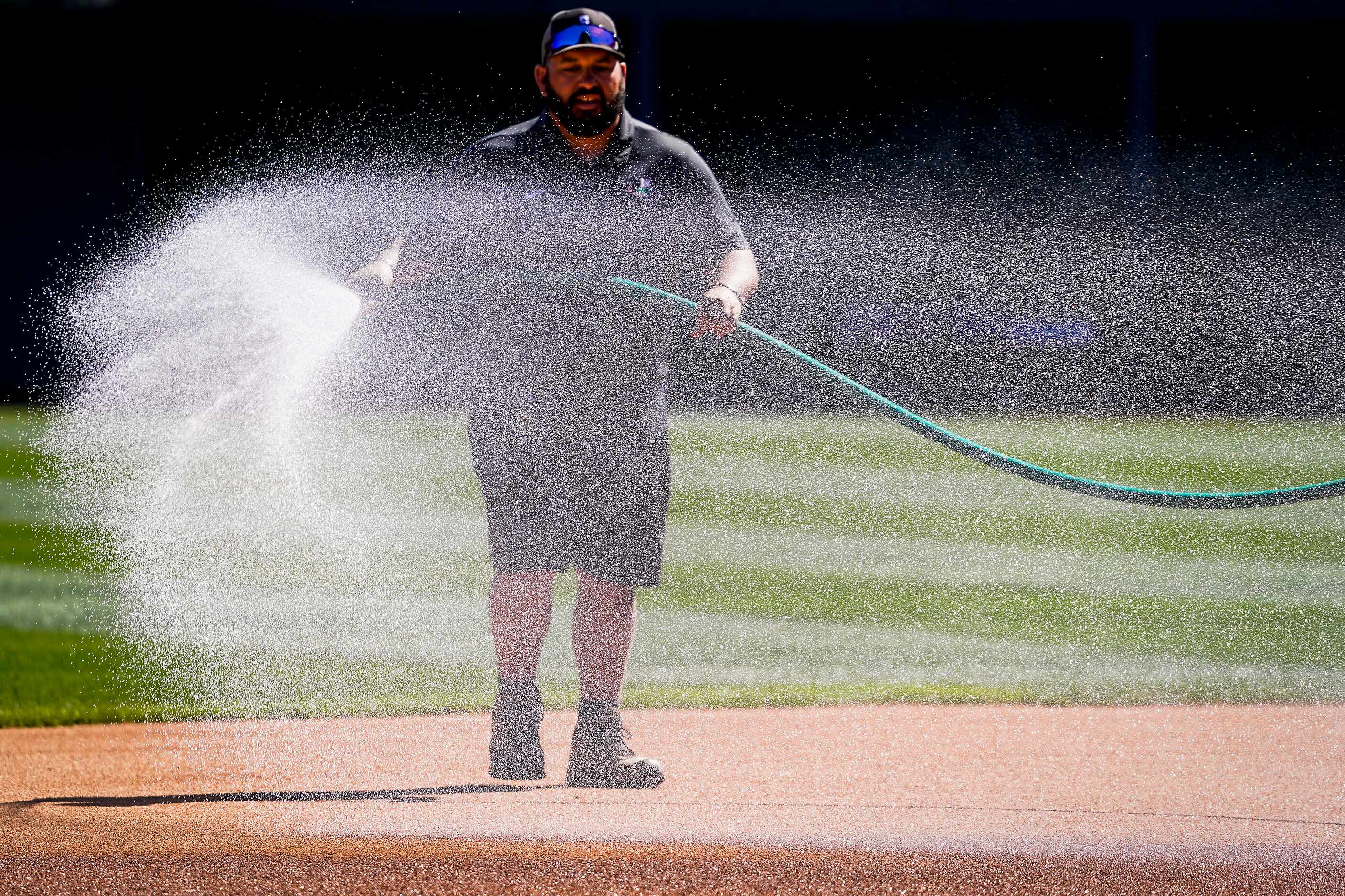 Groundkeepers prepare the field before a spring training game between the Texas Rangers and...