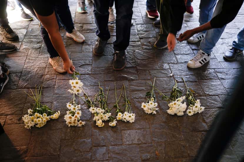 Gente deja flores durante una protesta contra el incendio en un centro de detención de...