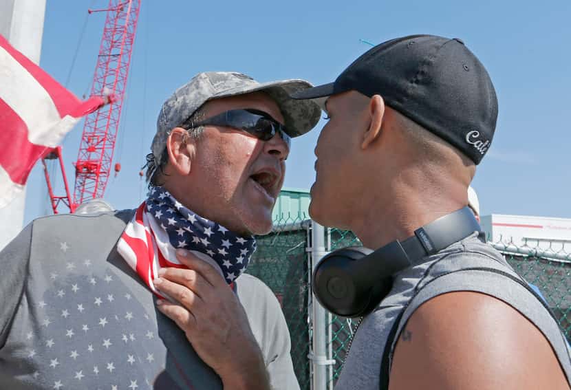 A gun-rights advocate (left) exchanges heated words with demonstrator Eric Cauley as Cauley...